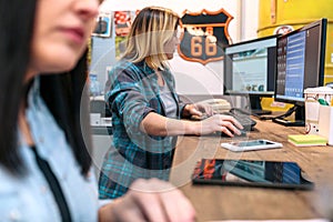 Blonde young woman checking orders in a computer received by ecommerce shop