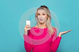 Blonde young woman a glass of milk on blue