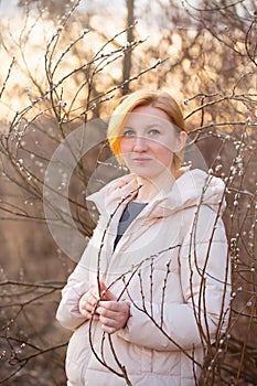 Blonde young woman near a flowering willow