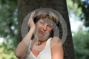 Blonde young woman in park listening to music on