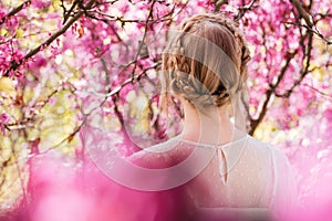 Blonde young woman standing in spring blooming garden
