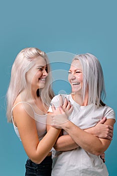 Blondehaired Mom and teenager daughter smiling on colorful backgroung. studio shoot with copy space photo