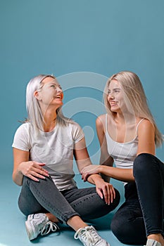 Blondehaired Mom and teenager daughter smiling on colorful backgroung. studio shoot with copy space photo