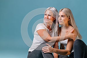 Blondehaired Mom and teenager daughter smiling on colorful backgroung. studio shoot with copy space photo