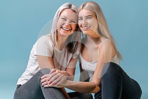 Blondehaired Mom and teenager daughter smiling on colorful backgroung. studio shoot with copy space photo