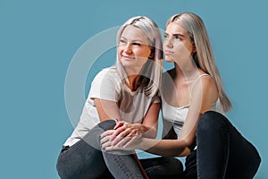 Blondehaired Mom and teenager daughter smiling on colorful backgroung. studio shoot with copy space photo