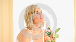 Blondhaired woman smelling a rose