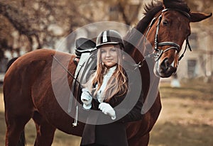 Blondie girl with a playful horse in summer horse park.