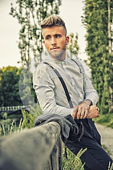 Blondish, blue eyed young man on wood fence