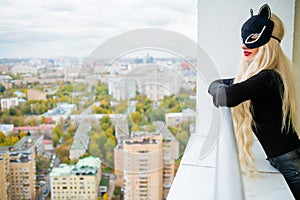 Blondy young woman in black cats mask is standing