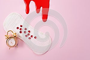 Blood, alarm clock and feminine hygiene pad with red glitter on pink background. First menstrual period concept