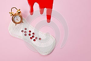 Blood, alarm clock and feminine hygiene pad with red glitter on pink background. First menstrual period concept