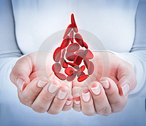 Blood cells in hands - shaped blood drop photo