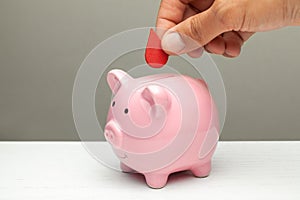 Blood donations. Man puts drop of blood in piggy bank