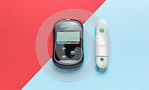 A blood glucose meter and a piercer on a red and blue background. The concept of getting rid of diseases