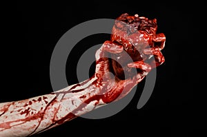 Blood and Halloween theme: terrible bloody hand hold torn bleeding human heart isolated on black background in studio