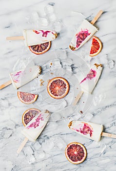 Blood orange, yogurt and granola popsicles on ice cubes