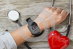 Blood pressure checking or tracking with smart watch and stethoscope on wooden table