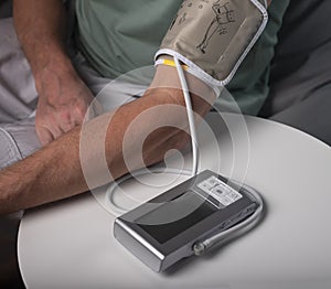 Blood pressure measuring and checking. Male hand on table with connected modern tool for cardio checkup at home