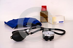 Blood pressure measuring device on a white table. Medications in the background