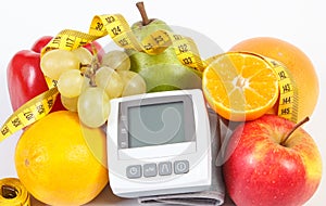 Blood pressure monitor, fresh ripe fruits with vegetables and tape measure