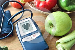 Blood pressure monitor with heart on screen and vegetables around