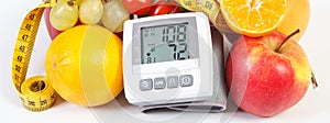 Blood pressure monitor with result of measurement, fresh ripe fruits with vegetables and centimeter, healthy lifestyle