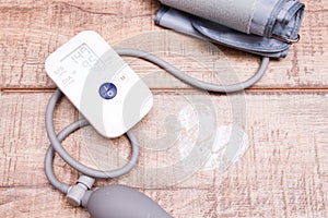 blood pressure monitor and white jar with tablets on a wooden background, heart made of white powder, pulse drawn