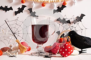 A blood-red drink for Halloween in the decorations for the holiday of spider webs, bats, crows, fly agarics, witch's