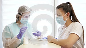 Blood sampling for analysis. Nurse takes blood from a finger from a patient. Blood test for covid-19.