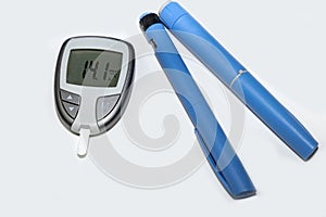 Blood sugar meter with test strips indicates high blood sugar levels and injection pen for diabetes.