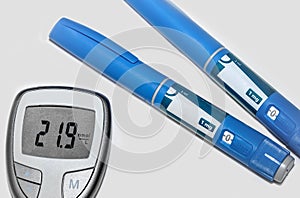 Blood sugar meter with test strips indicates high blood sugar levels and injection pen for diabetes.