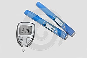 Blood sugar meter with test strips indicates high blood sugar levels and injection pen for diabetes.