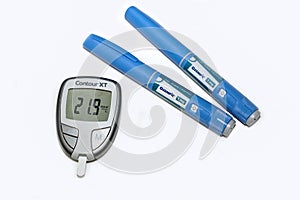 Blood sugar meter with test strips indicates high blood sugar levels and Ozempic injection pen for diabetes.