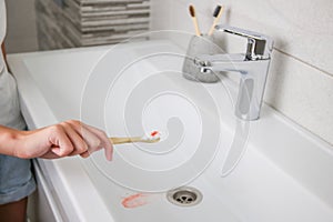 Blood on toothbrush on background of sink. Selective focus on the toothbrush