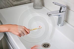 Blood on toothbrush on background of sink. Selective focus on the toothbrush