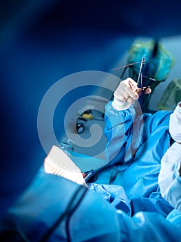 Bloodied hands of surgeons in sterile latex gloves with surgical instruments with traces of blood