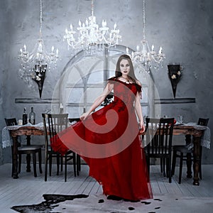 Bloodthirsty female vampire in red dress. Medieval interior