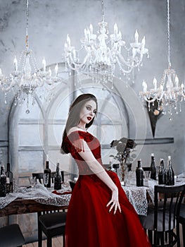 Bloodthirsty female vampire in red dress. Medieval interior