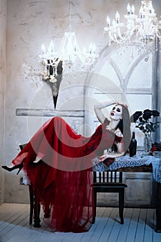 Bloodthirsty female vampire in red dress. Medieval interior