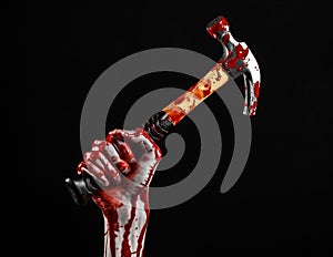 Bloody halloween theme: bloody hand holding a bloody hammer isolated on a black background
