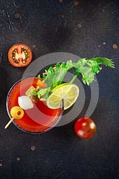 Bloody Mary cocktail with garnish on a black background, shot from above