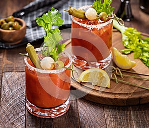 Bloody mary cocktail with garnishes on rustic wooden table