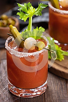 Bloody mary cocktail with garnishes on rustic wooden table