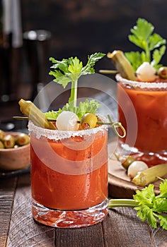 Bloody mary cocktail with garnishes on rustic wooden table