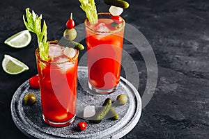 Bloody Mary Cocktail in glasses with garnishes. Tomato Bloody Mary ice cold drink with fresh celery, pickles and lime