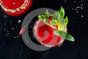 Bloody Mary cocktail with lime and celery, shot from the top on a black background