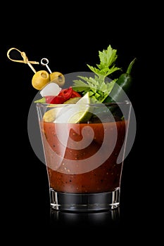 Bloody mary cocktail mix with red and green pepper and olive, celery,olives and lime slice on black background