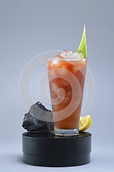 Bloody Mary cocktail with vodka and tomato juice in a tall glass on a dark podium,