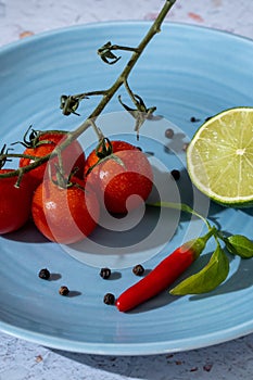 Bloody Mary ingredients concept. A branch of fresh and red cherry tomatoes, black pepper seeds, a lemon and a spicy